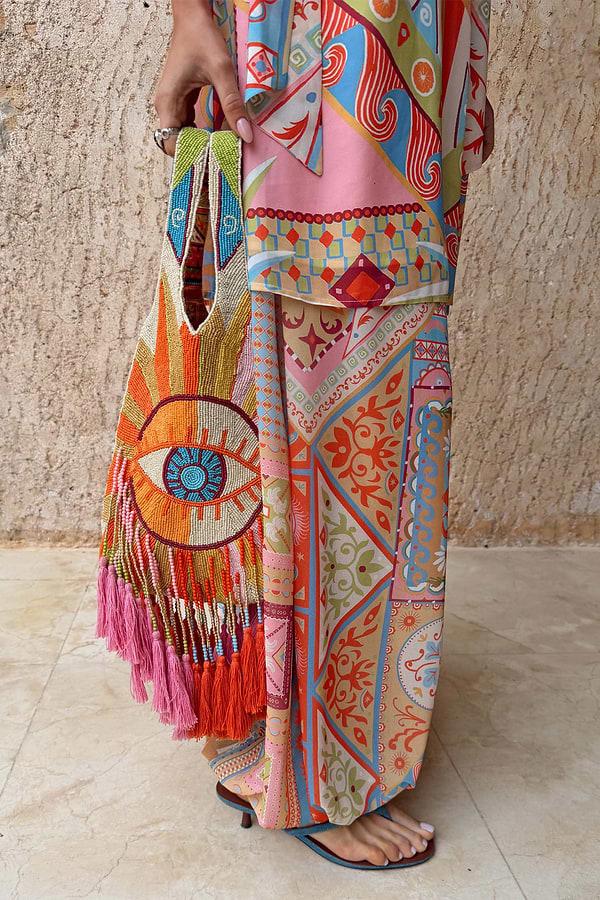 Dolce Vita Eye Bag with hand-embellished beads, an eye motif and tassel trim, styled with a matching print set.