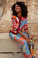 Dolce Vita Hollie Cardigan with eye graphics and swirl motifs, styled on a model sitting against a stone wall.
