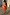 Thumbnail for Blurred Floral Ella Mini Dress in peach orange with flute sleeves and a tiered ruffle skirt styled off the shoulder.