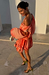 Blurred Floral Ella Mini Dress in peach orange with flute sleeves and a tiered ruffle skirt styled off the shoulder.