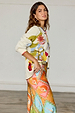 Multi Enchanted Cardigan in cream cotton knit with colourful motifs and ribbed trim, styled with a printed skirt.