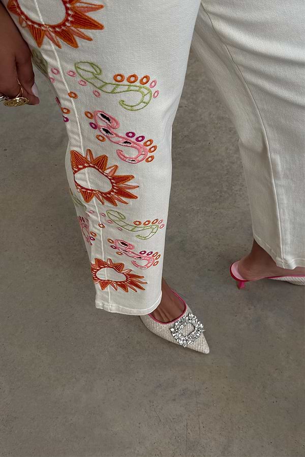 Ecru Enchanted Jeans featuring sun and abstract motif embroidery on cotton denim.