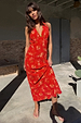 Red Floral Halter Dress with a vintage floral print, green trim and bow detail, shown on a model outdoors.