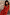 Thumbnail for Red Floral Halter Dress with green trim and bow detailing, worn by a model against a rustic stone wall background.