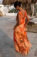Iconic Blurred Floral Sofia Dress in burnt orange with tie-knot shoulders, styled for a sunny vacation.