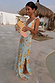 Sky Blue Floral Sofia Dress featuring a side slit and tie shoulders, paired with a beaded clutch outdoors.