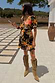 Black Sofia Mini Tea Dress with an orange and pink floral print and frill hem, styled with tan fringe boots.