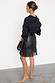 Black Vegan Leather Mini Fringe Jaspre Skirt featuring a wrap tie waist and fringe hem, shown on a model.