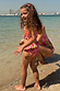 Girls Pink Fruit Crop Bikini Set with Mediterranean fruit print and frill details on a beach vacation.