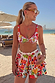 Fruit Stamps Mediterranean fruit print bikini top and tiered frill shorts on a beach, perfect for vacation.