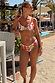 Fruit Stamps bikini with a Mediterranean citrus print, low-rise fit and pink whipstitch trim, on a sunny beach.