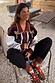 Geometric Knit Cardigan with embroidered palm motifs and autumnal tones, worn by a 5ft4” model in size M sitting outdoors.