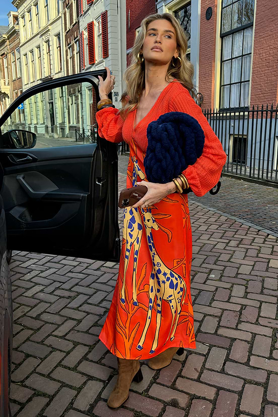 Giraffe Emma Dress with an orange crochet bodice and printed viscose skirt, styled with boots on a cobblestone street.