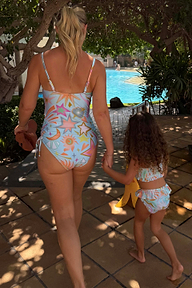 Girl's blue Starburst Crop Bikini Set with frill trims, walking towards a pool on vacation.