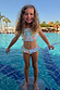 Blue Starburst Crop Bikini Set with a smocked top and frill trims, worn by a girl in a sunny vacation pool.
