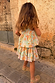 Girl's blue cotton Starburst Skirt Co-ord with a sun and star print, peplum top and tiered skirt, seen from behind.