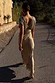 Gold Sequin Elodie Dress with a V-back sequin bodice and satin skirt, viewed from behind outdoors.