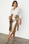 Gold vegan leather Jaspre wrap skirt styled with a white button-down shirt and blue heels.