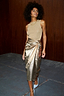 Thumbnail for Gold Vegan Leather Jaspre Skirt, a metallic wrap midi styled with a neutral knit top and blue heels.