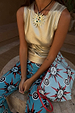 Metallic Gold Ribbed Tank Top styled with vibrant sun-print trousers and a matching clutch bag.