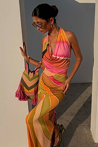 Green Abstract Sabine Dress in a multicoloured jersey with a cowl halter neck, styled with a beaded bag.