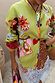 Green Enchanted Cardigan with iconic motifs and multi-coloured trim, styled over a patterned slip dress.