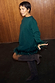 Multi-wear Bottle Green Jamie Jumper with feather cuffs, designed in London and styled with tall brown boots and a skirt.