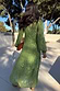 Olive green Harmony Dress with shimmering gold jacquard animal print and a tiered skirt, seen from the back outdoors.
