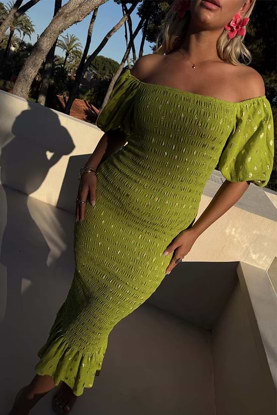 Olive Jojo Dress with gold fleck print, shirred body and puff sleeves, worn off-the-shoulder outdoors.