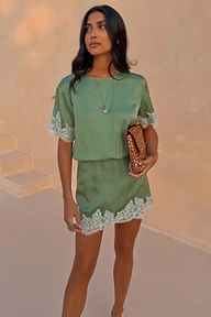 Green mini dress with cream lace trims and shift silhouette, styled with a leopard print clutch for vacation.