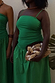 Green Lola Mid-axi Dress with a ruched top and cotton skirt, styled with a beaded clutch for a vacation look.