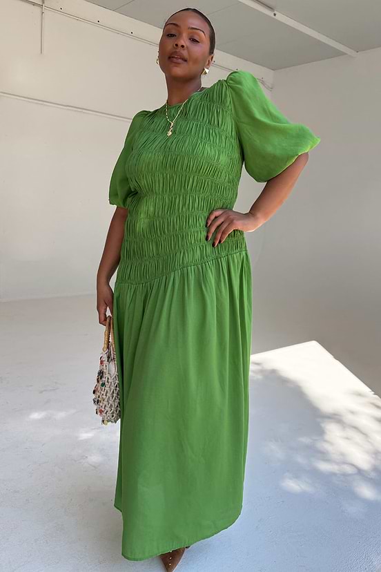 Green Shirred Nara Dress with a shirred bodice, puff sleeves and pleated skirt on a curve model.