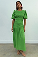 Green Shirred Nara Dress featuring a smocked bodice, short puff sleeves and a flowing pleated skirt.