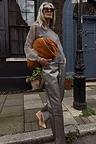 Gunmetal Vegan Leather Trousers styled with a sheer grey top and tan suede bag on a London street.