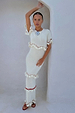 Ivory and Red Harper Dress, a cream knit midaxi with crochet scallop trim and white tassels, styled in a white archway.