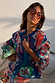 Hexagon Orange Sunglasses with light-tinted lenses, worn with a patterned knit cardigan for a vacation look.