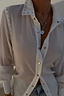 Deloris I Love You Lariat Necklace in brass with a chunky chain and spinning pendant, styled over a white shirt.
