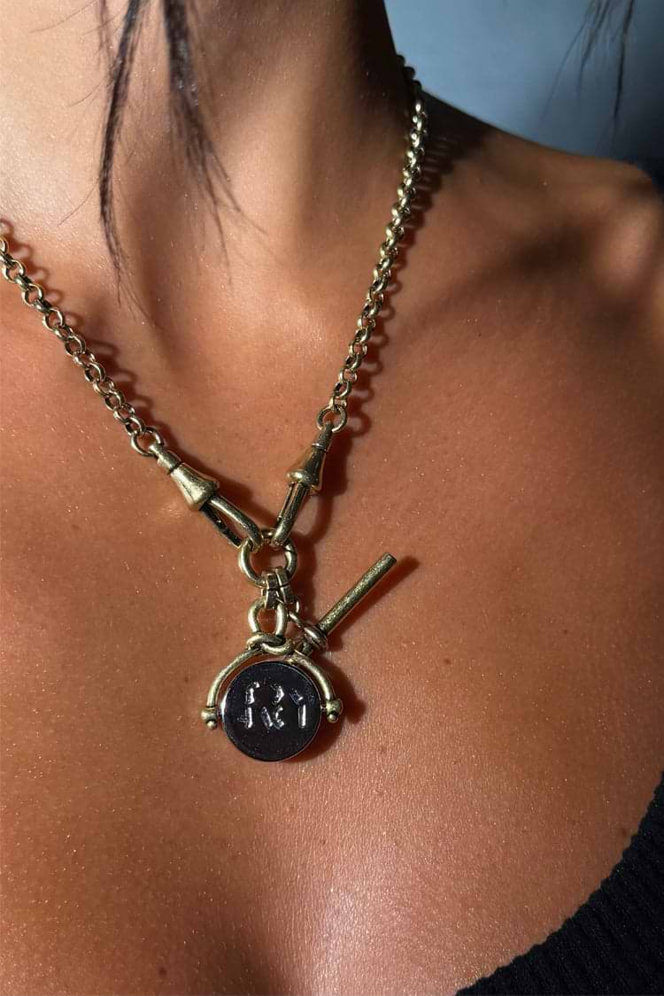 Gold-tone Deloris I Love You Lariat Necklace with a chunky brass chain and spinning engraved pendant on a model.