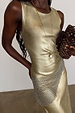 Gold-tone Deloris I Love You Necklace featuring a lariat drop and spinning pendant, styled over a metallic gold dress.