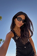 Deloris Thin Chain I Love You Necklace with a spinning brass pendant, styled for a sunny vacation look.