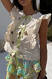 Cream Isla Tia Top featuring green tie-front closures, lace trim and ruffles with embroidered NFD motifs.