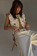 Cream Isla Tia Top featuring lime green multi-wear ties, lace trim, and embroidered motifs on a seated model.