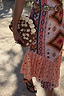Jaden Beaded Clutch Bag with brown and white beadwork and cream spheres, held against a colourful print dress.