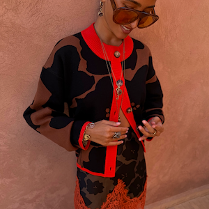Tan Jaden Floral Jacquard Cardigan with red ribbed trims, styled with layered gold jewellery and matching skirt.