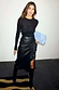 Thumbnail for Black Vegan Leather Ruffle Jaspre Skirt featuring a wrap tie and ruffle trim, styled with a black top and boots.