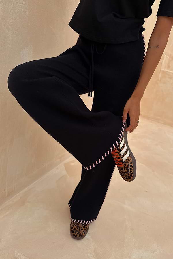 Black Night Garden Knit Jogger featuring pink blanket stitch detailing and wide legs, styled with leopard print trainers.