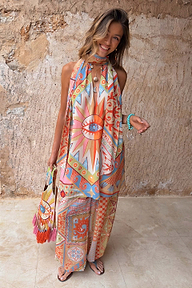 Dolce Vita Josie Mini Dress in sunset tones with an eye motif and halterneck scarf tie, styled for vacation.