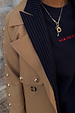 Deloris Key Necklace with a red gemstone on a brass link chain, layered over a navy pinstripe blazer.