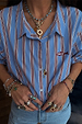 Deloris Thin Chain Key Necklace with a gold-tone key and red gem, styled with layered jewelry over a striped shirt.