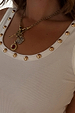 Deloris Key Necklace with iconic key and red gemstone charms on a polished brass chain, styled for layering over a vest.